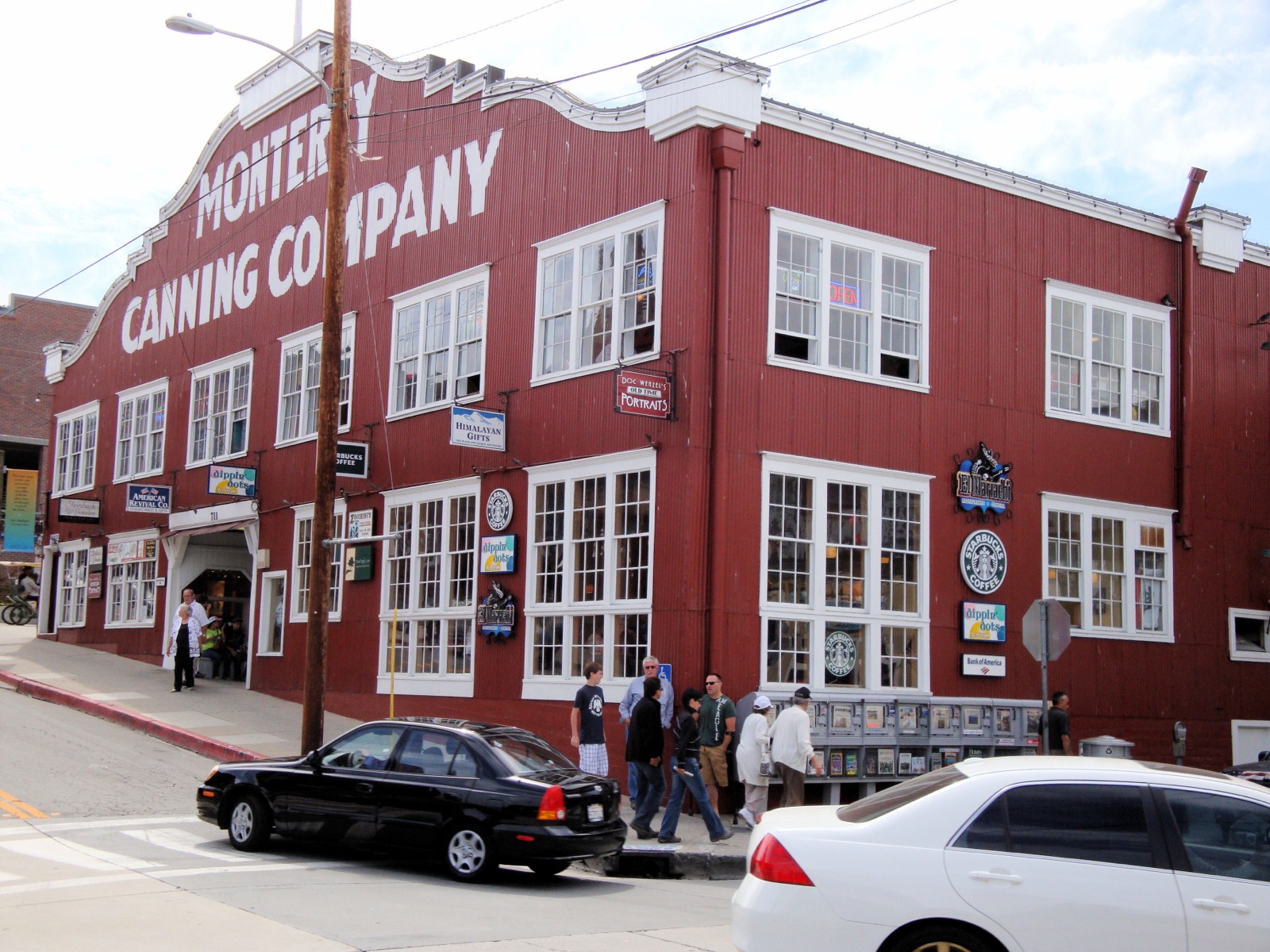 Historic Cannery Row streetscape with waterfront buildings and pedestrians in Monterey, California.