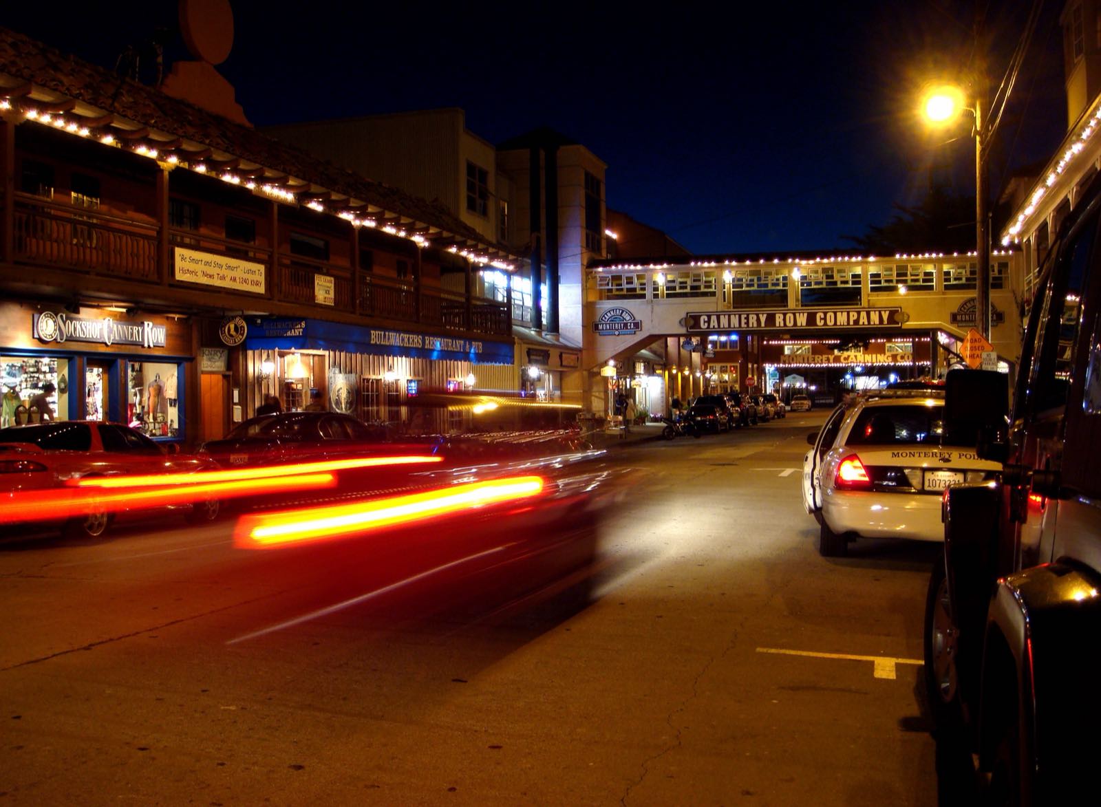 Illuminated storefronts and historic buildings along Cannery Row at night in Monterey.