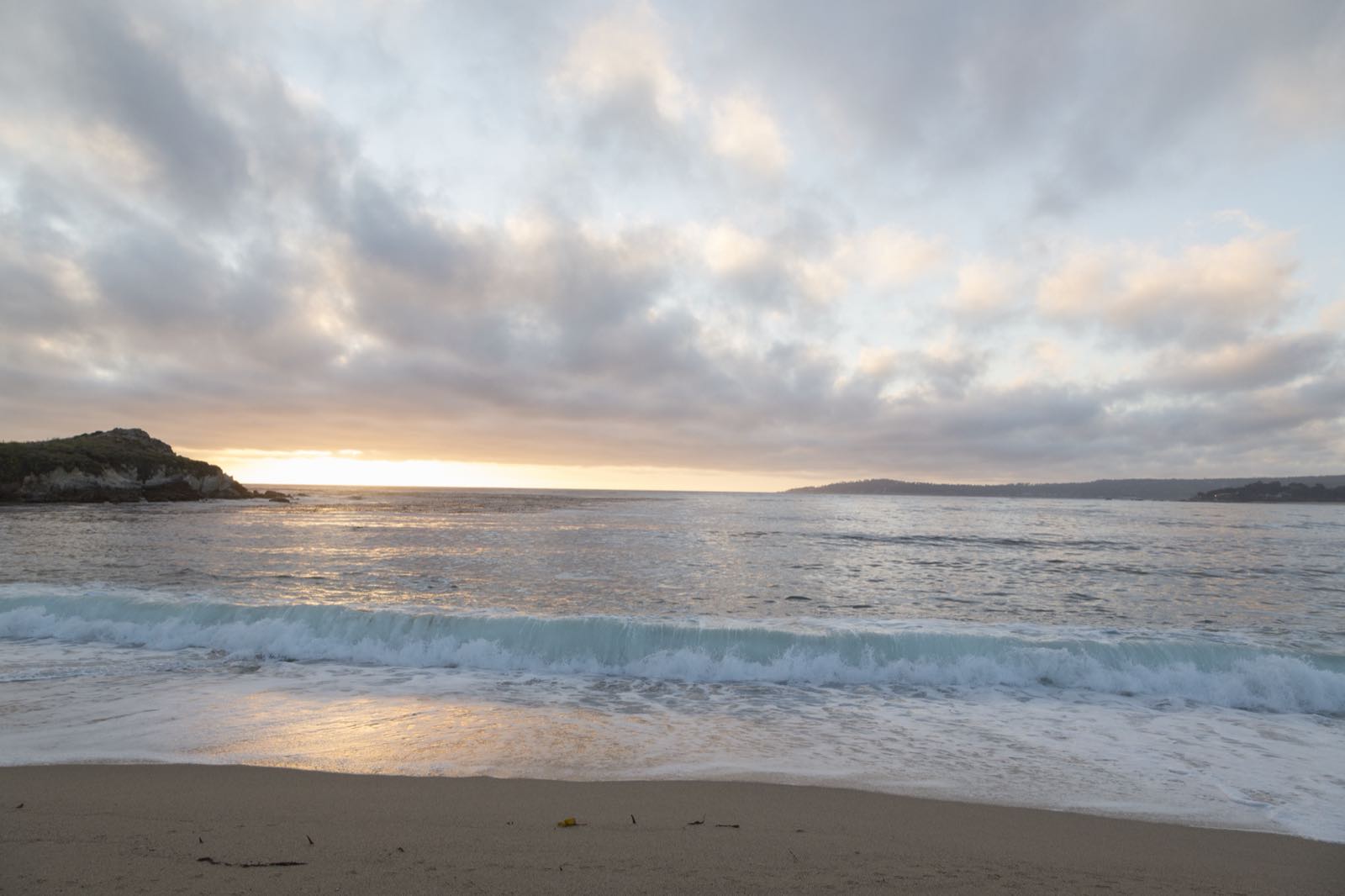 Golden sunset light over rocks and Pacific surf along the Monterey coast.
