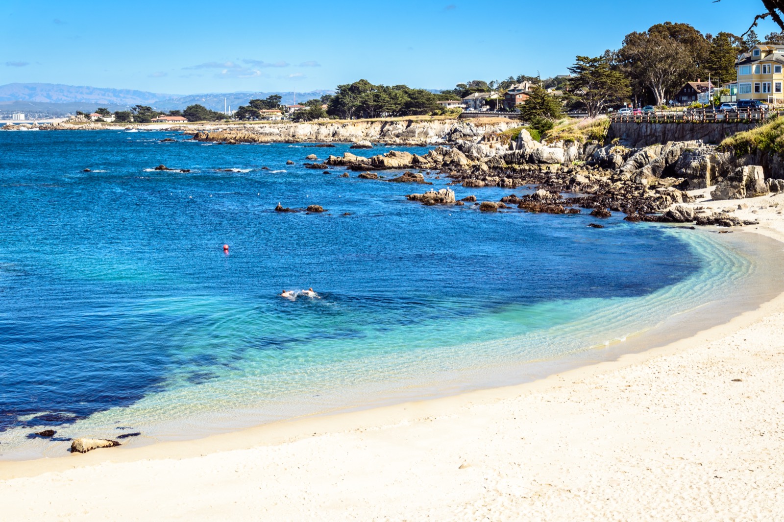 Rocky Pacific Grove shoreline at Lovers Point with ocean, surf, and cypress-lined coast.