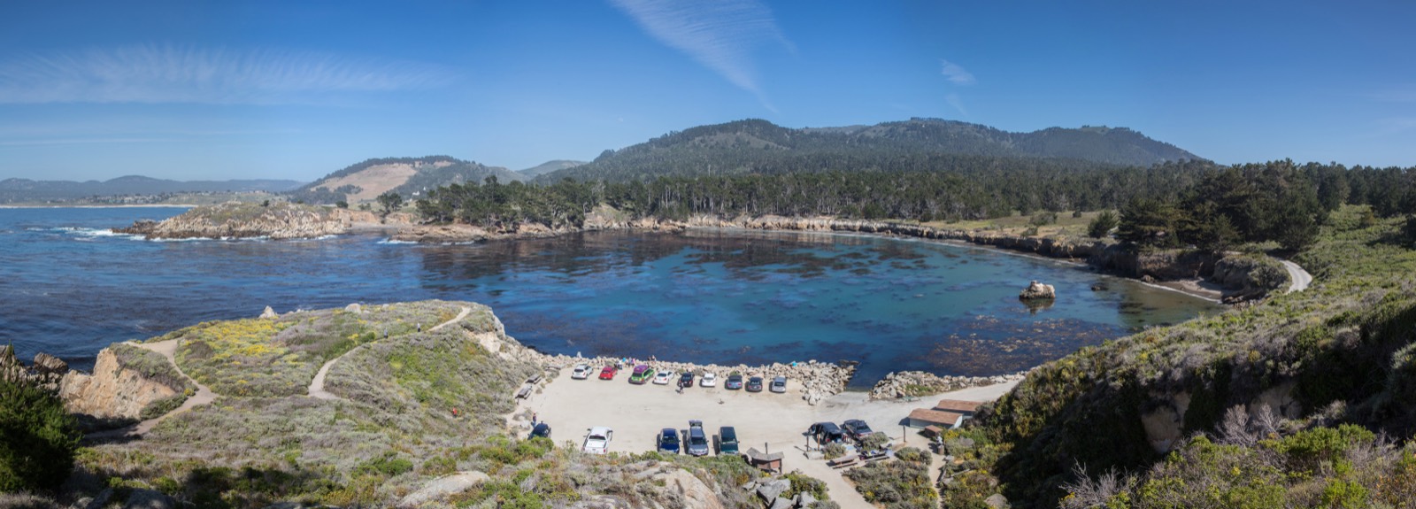 Panoramic view of Whaler's Cove at Point Lobos with rocky shoreline, blue water, and coastal vegetation.